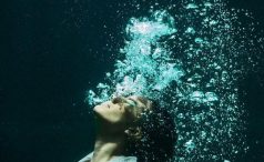 Woman underwater in suit with air bubbles