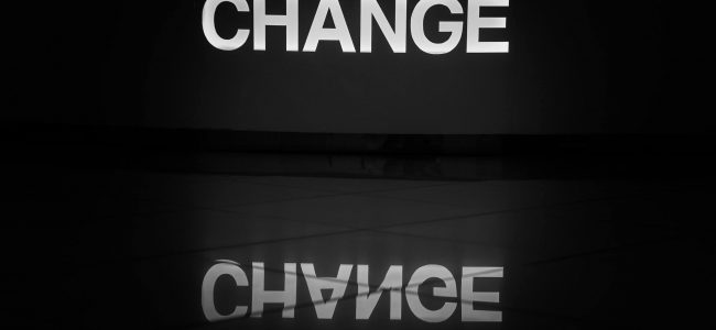The word change illuminated in white and reflected on a tiled floor