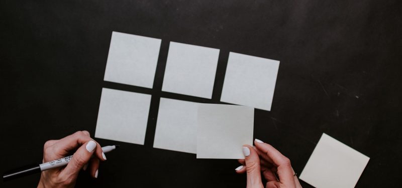 Person holding white post-it notes and organizing