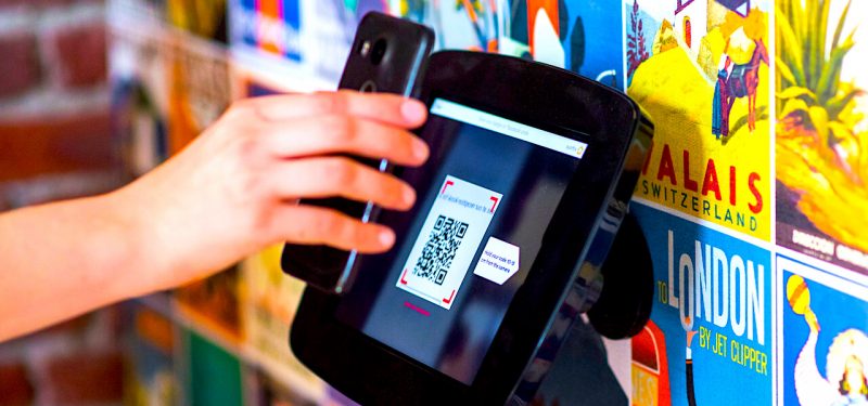 A QR code being scanned by a smartphone-wielding user