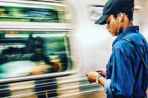 Person listening to podcast on phone as subway goes by