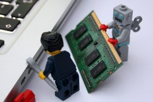 Robot lego helping lego man fix computer