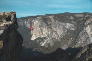 Man in red t-shirt walking a highline at Taft Point, Yosemite.