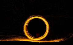 Burning steel wool being swirled in a circle at night to form a zero with slow exposure