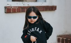 A sassy child in black fairfax sweatshirt and red sun glasses