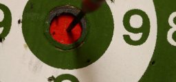Dart in the red bullseye on green and wite concentric circled dart board
