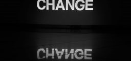 The word change illuminated in white and reflected on a tiled floor