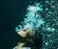 Woman underwater in suit with air bubbles