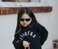 A sassy child in black fairfax sweatshirt and red sun glasses