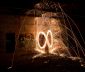 Long exposure nightime photograph of burning steel wool swung in an infinity pattern